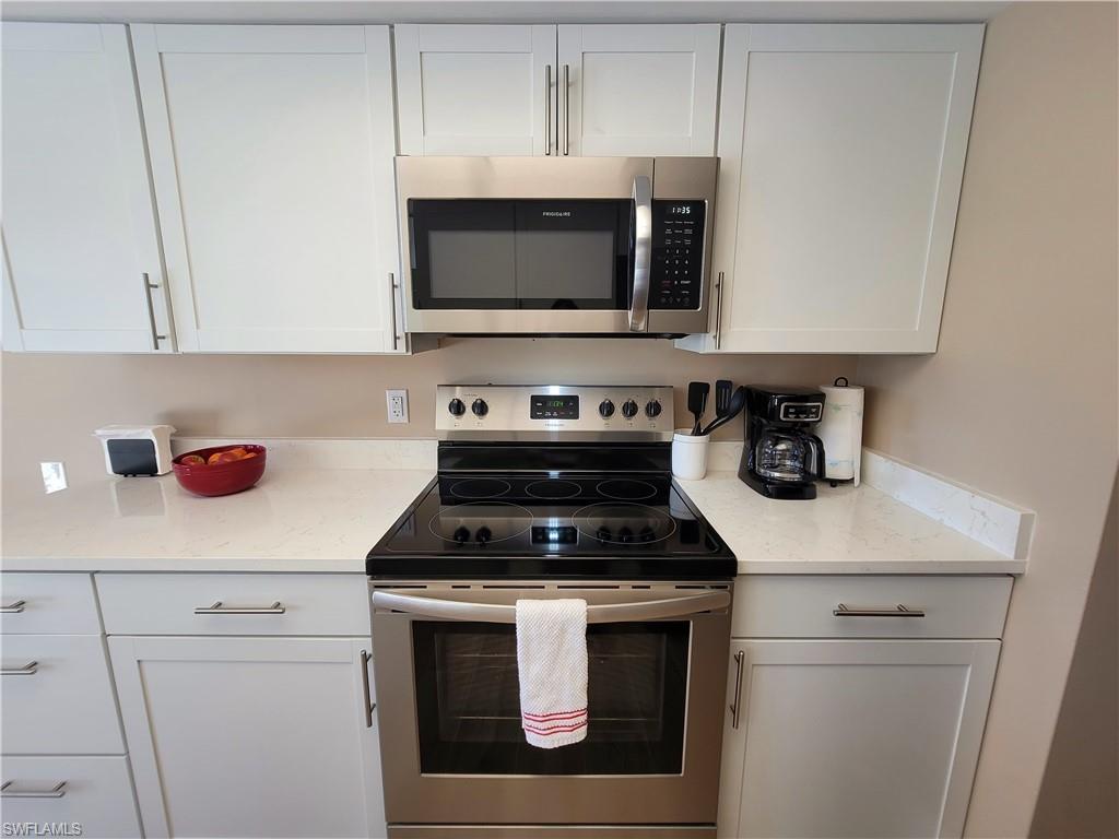 Contemporary kitchen featuring white shaker-style cabinetry, stainless steel appliances, and light-toned countertops