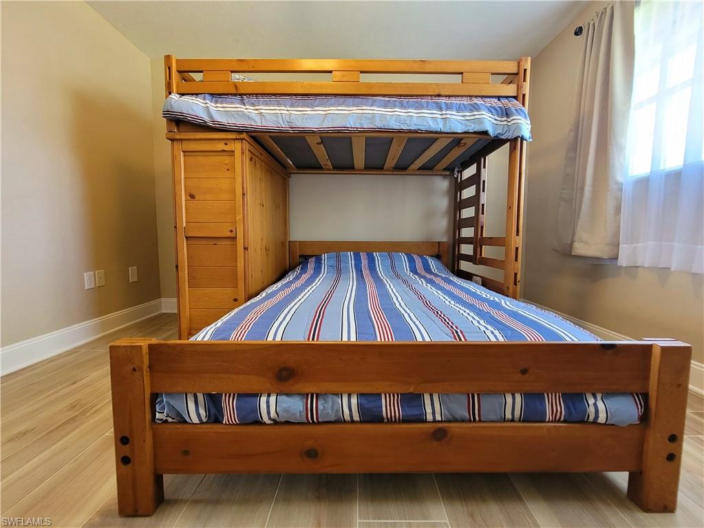 Room featuring wood-finish flooring, white baseboards, and light beige wall paint