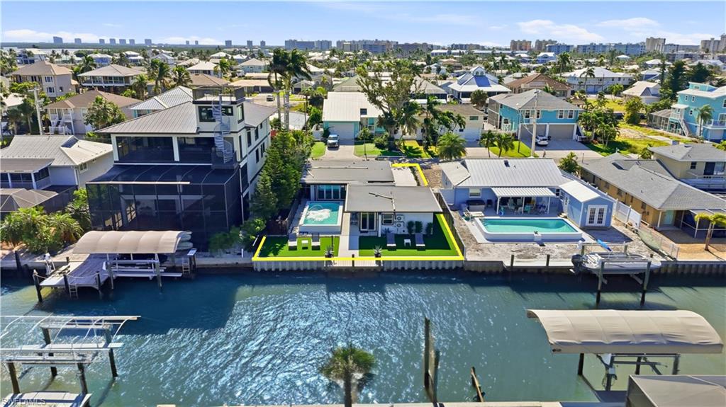 Rear view of property with pool, yard, and water views - Virtually Edited Image