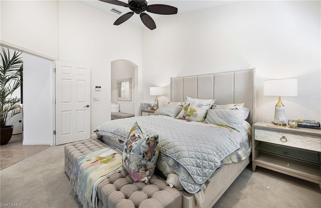 Carpeted bedroom featuring a high ceiling and ceiling fan