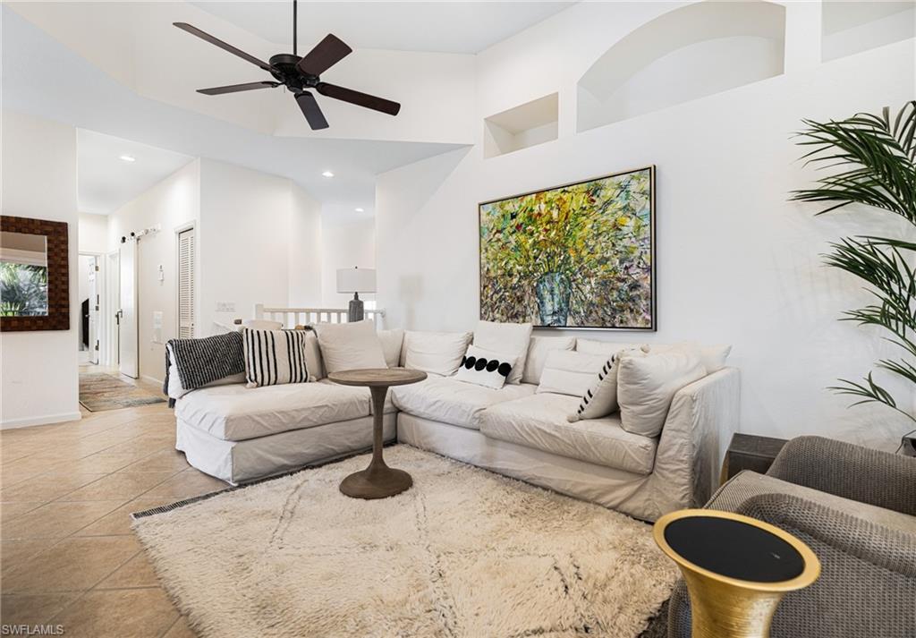 Tiled living room with ceiling fan and a towering ceiling