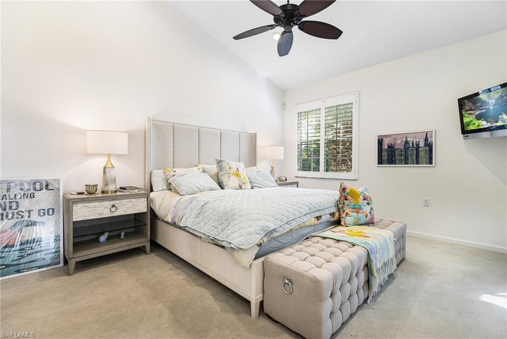 Carpeted bedroom featuring lofted ceiling and ceiling fan