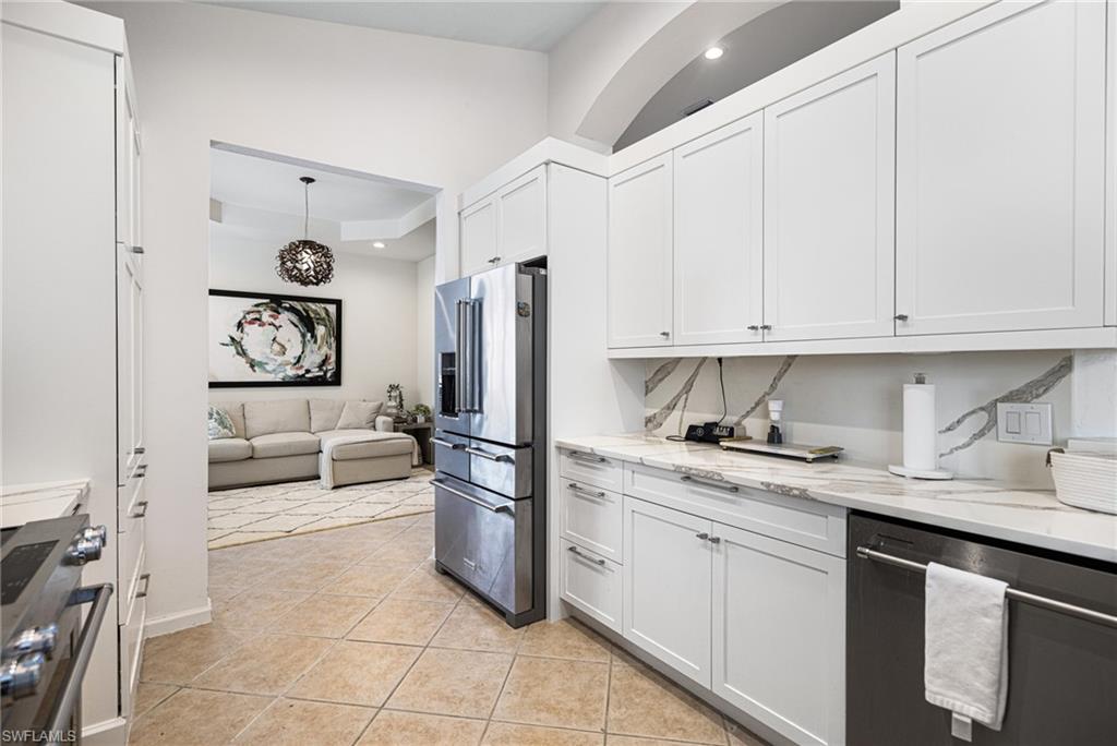 Kitchen with light tile patterned flooring, white cabinetry, light stone countertops, and stainless steel appliances
