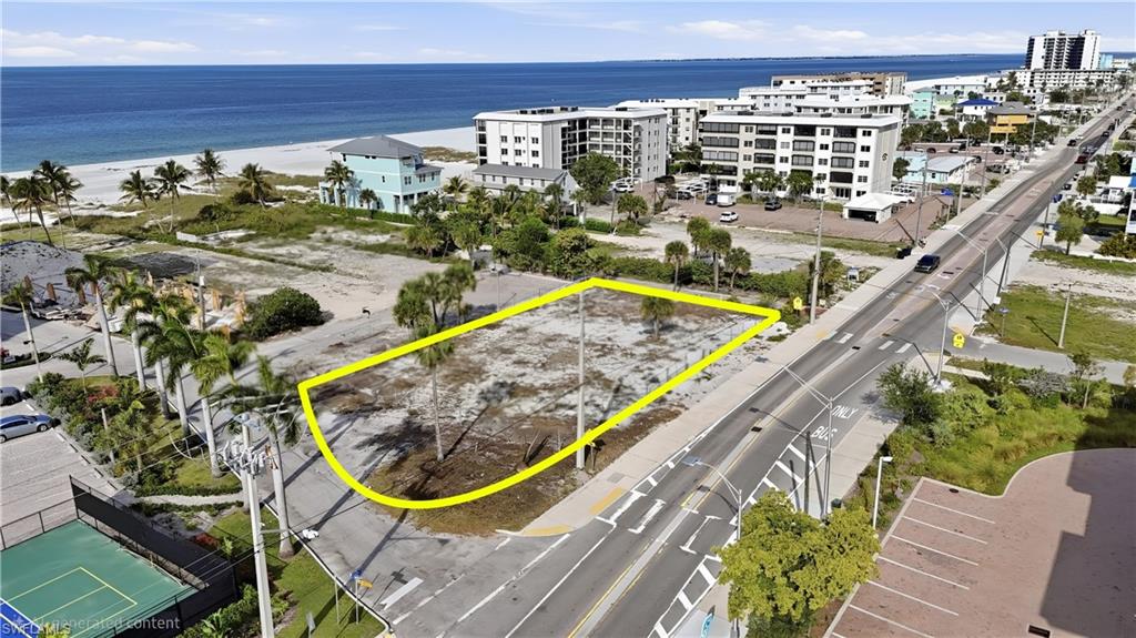 Generous land parcel featuring proximity to the gulf, a street-front position, mature palm trees, and existing utility poles - Virtually Edited Image