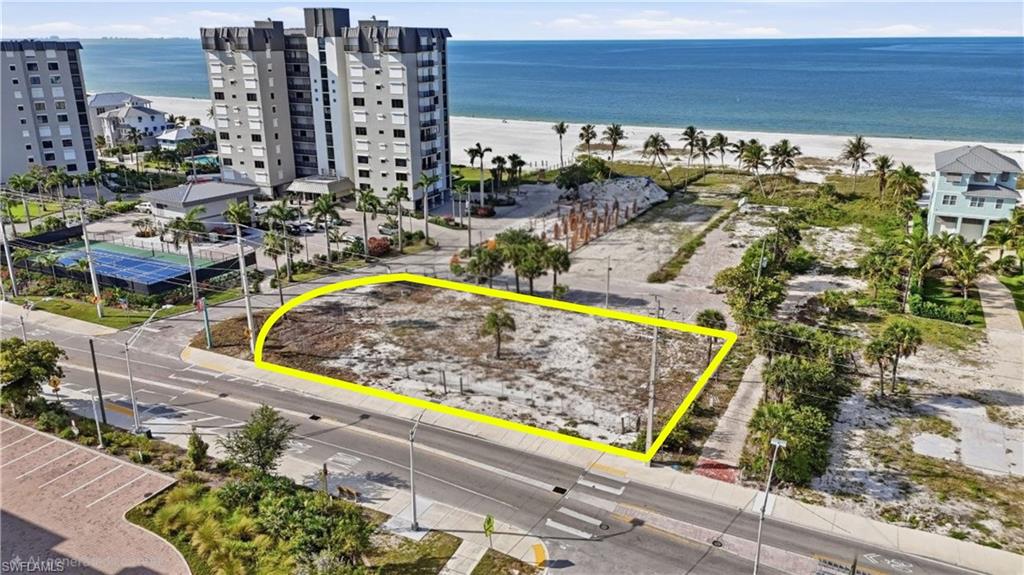 Cleared lot with street frontage, featuring a single palm tree, and a sidewalk along its perimeter - Virtually Edited Image