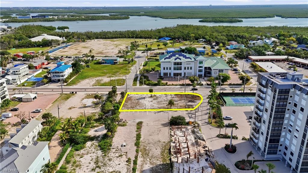 Cleared vacant lot with street frontage, featuring established palm trees and proximity to waterfront - Virtually Edited Image