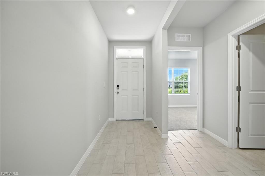 Entry foyer featuring wood-finish tile flooring and crisp white baseboards