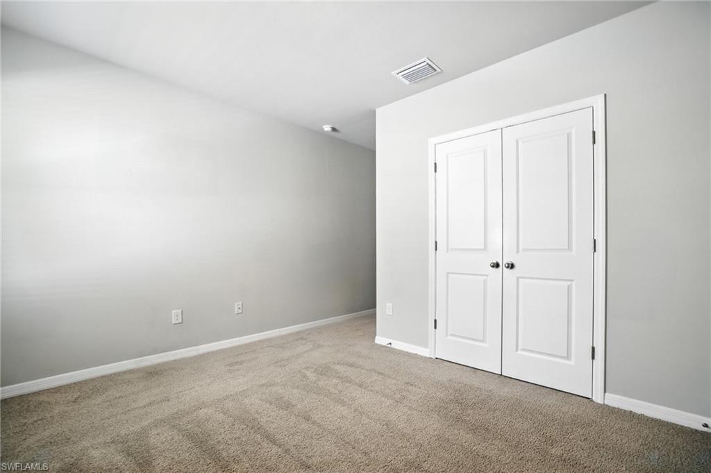 Carpeted room featuring light gray walls, white baseboards, and dual white paneled doors with dark hardware
