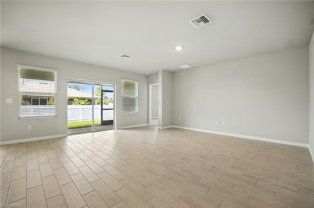 Spacious interior room featuring light-toned tile flooring, neutral wall paint, and recessed lighting