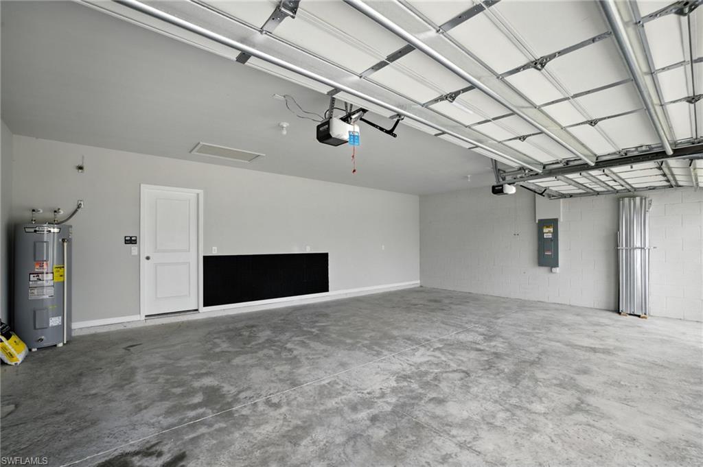 Spacious two-car garage featuring a concrete floor, light gray painted walls, a white service door, and an overhead garage door with an automatic opener