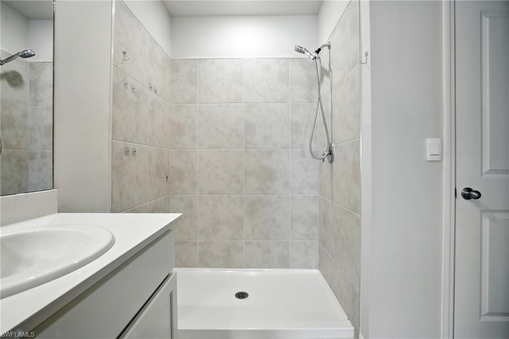 Shower enclosure with light-toned tiled walls and a white base