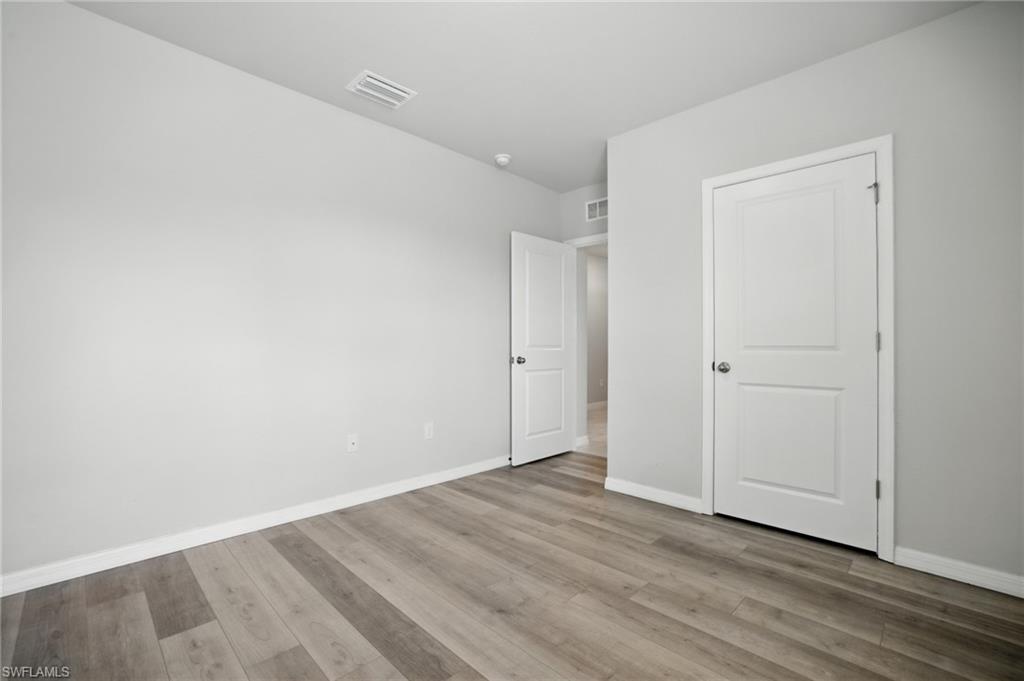 Room featuring wood-finish flooring, light gray wall paint, and white trim