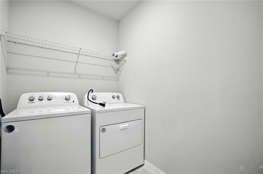 Dedicated laundry area featuring a wire storage shelf, white walls, and a light-toned flooring