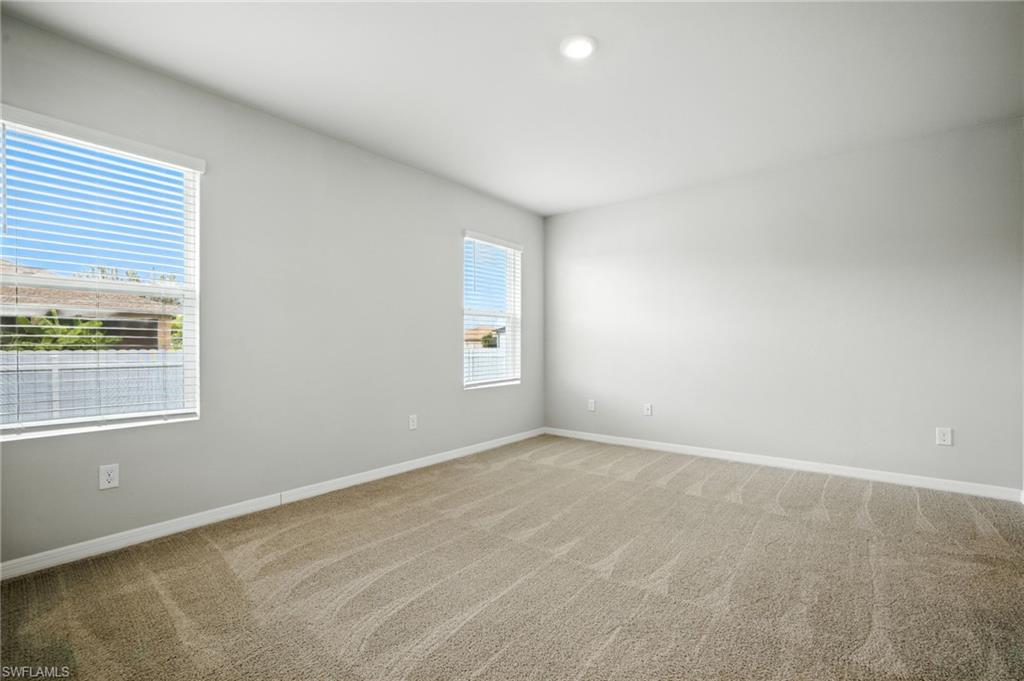Spacious room featuring neutral paint, two windows with blinds, a recessed ceiling light, and light-toned carpet flooring
