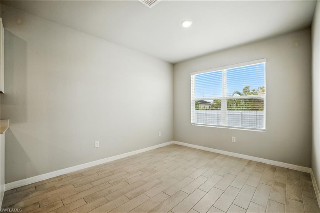 Open room featuring wood-finish tile flooring, a large window with blinds, and recessed lighting