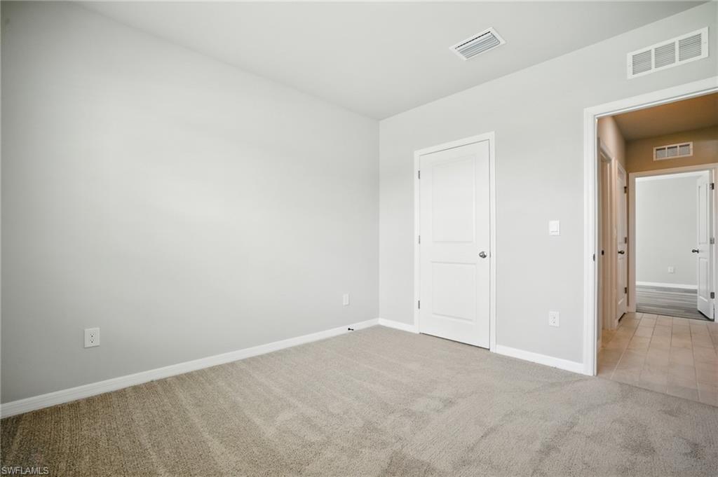 Spacious room featuring neutral wall paint, light-toned carpeting, white trim, and a white two-panel door