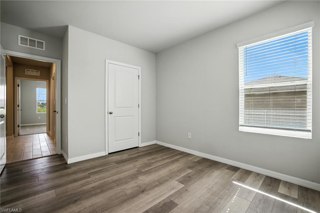 Room featuring wood-finish flooring, light gray wall paint, and white baseboards