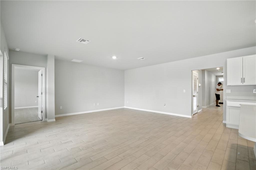 Spacious room featuring light-toned tile flooring, recessed lighting, and crisp white baseboards