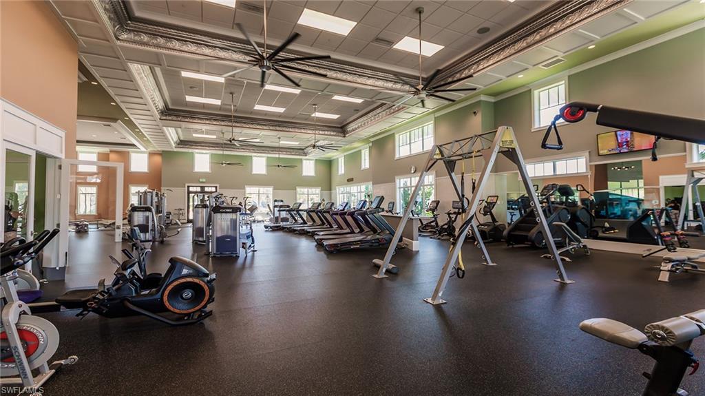 Gym with a ceiling fan, a high ceiling, crown molding, and a drop ceiling