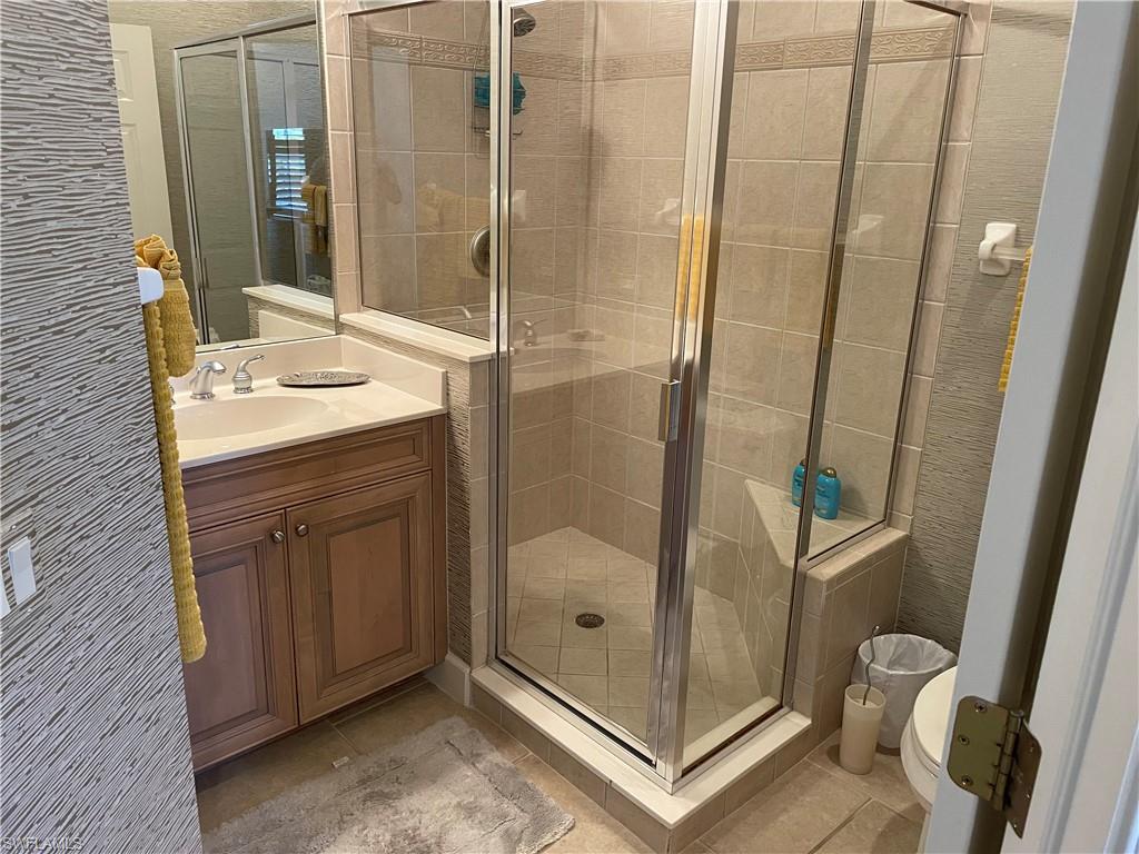 door, vanity, tile patterned floors, and toilet