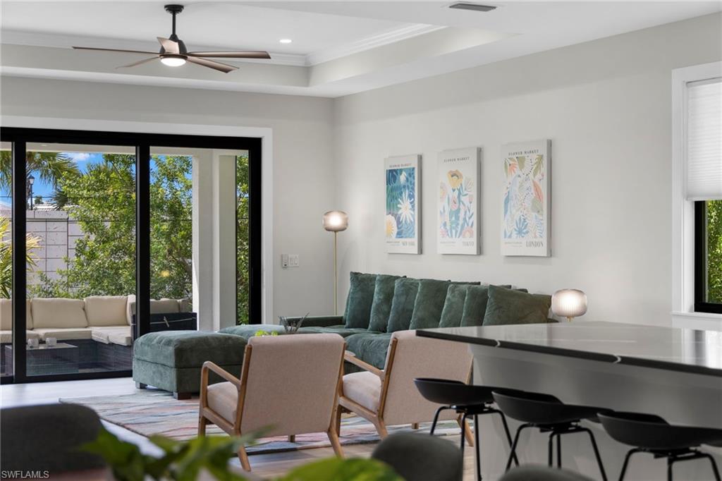 Spacious living area featuring a tray ceiling with recessed lighting and ceiling fan