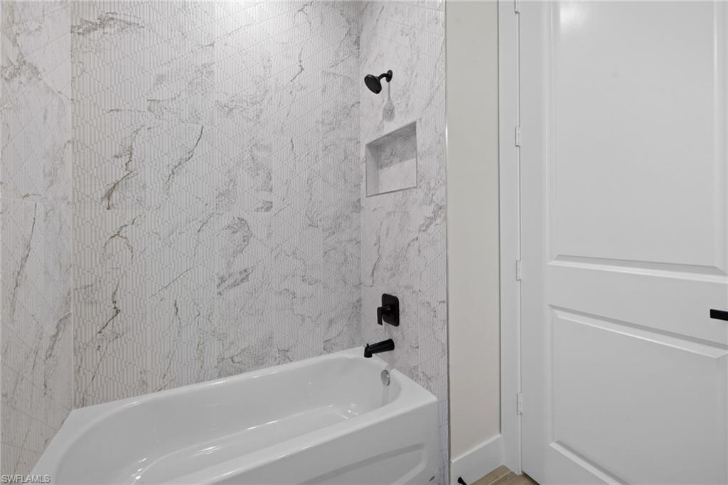 Bathtub with a matte black shower head and faucet, featuring a recessed niche