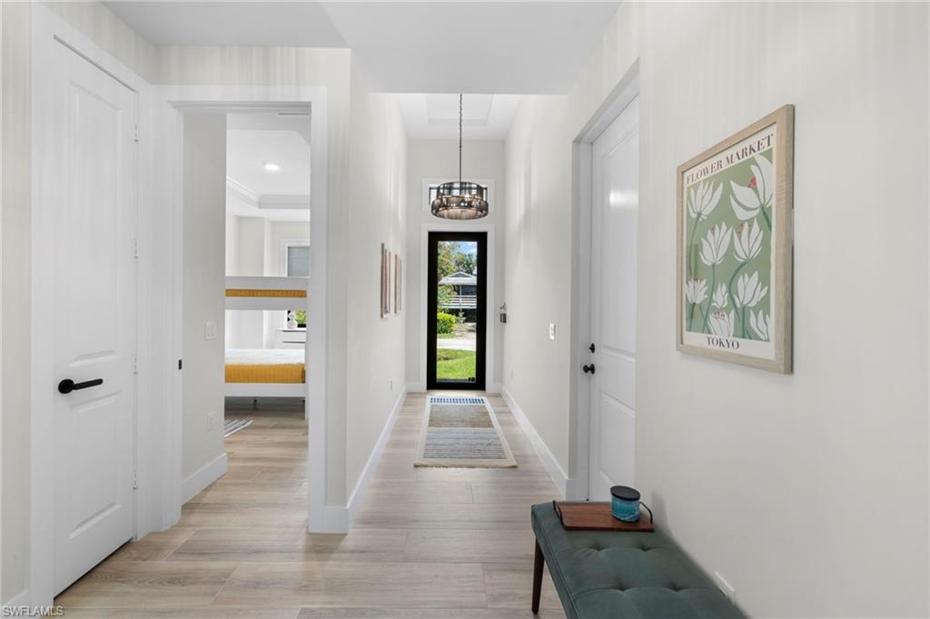 Entryway featuring wood-finish flooring, a modern drum pendant light, and a framed glass entry door