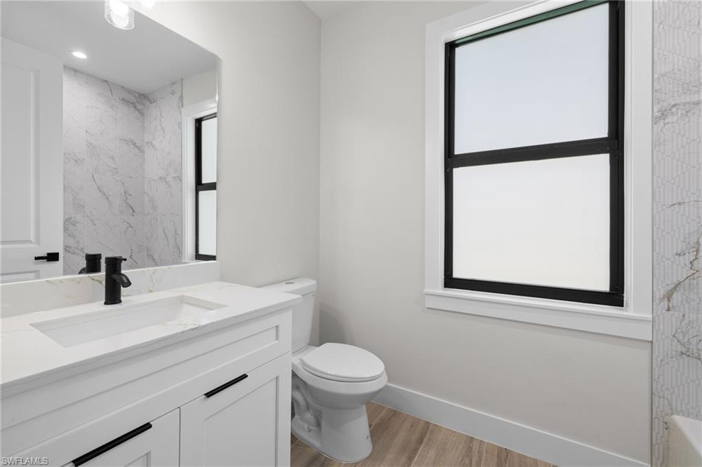 Bathroom featuring a white vanity with integrated sink, quartz-finish countertop, and matte black faucet