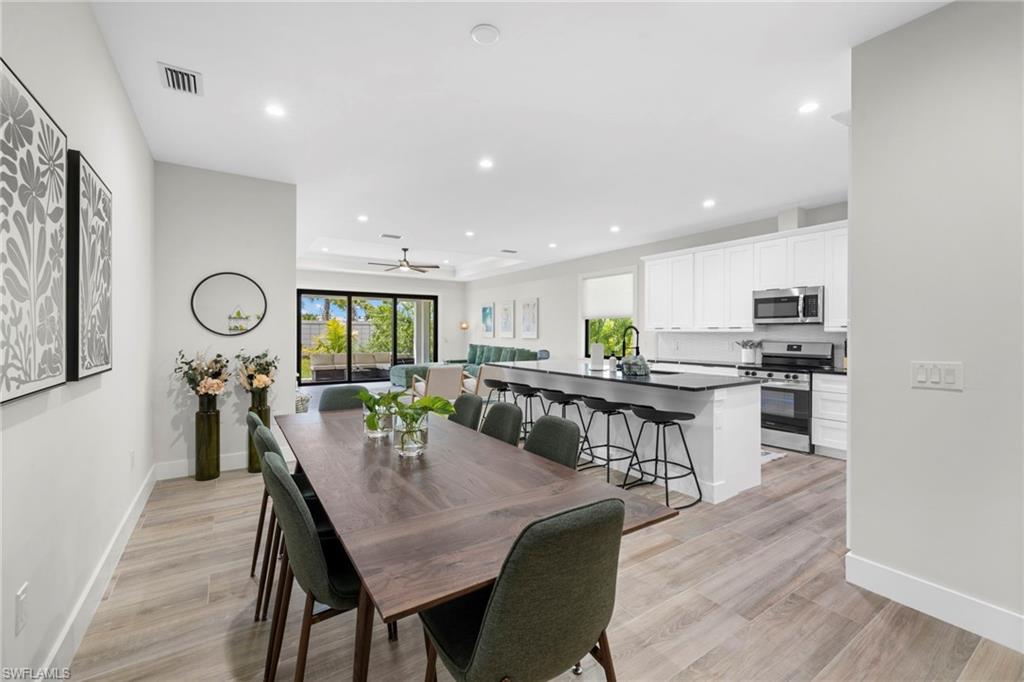 Open-concept living space featuring wood-finish flooring, recessed lighting, and a tray ceiling