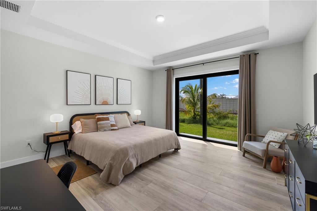 Spacious interior featuring wood-finish flooring, a tray ceiling, and light gray walls