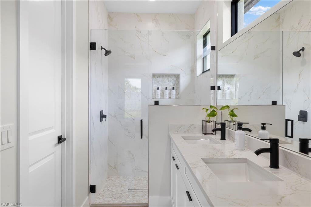 Bathroom featuring a dual vanity with undermount sinks, stone countertops, and matte black fixtures