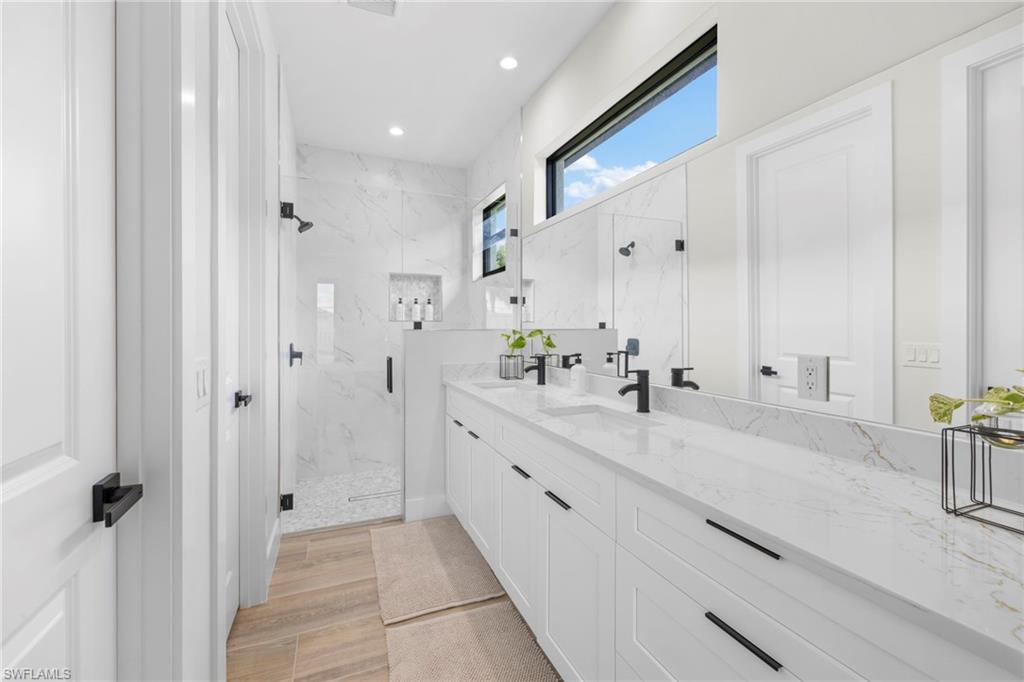 Bathroom featuring dual vanities with white cabinetry, matte black hardware, and stone countertops