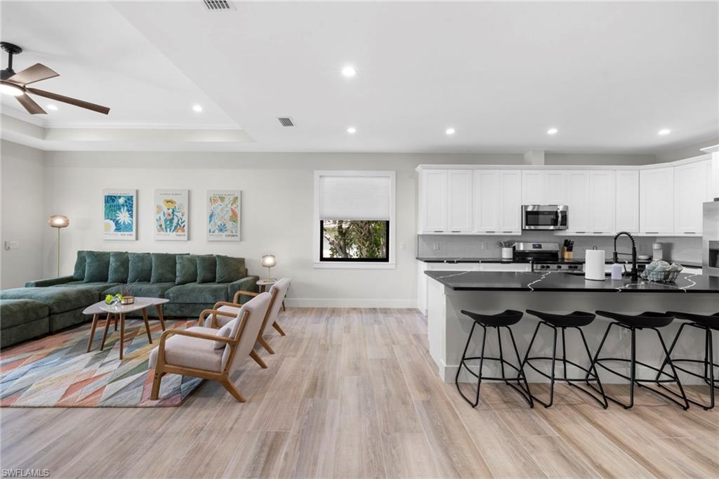 Open-concept living space featuring wood-finish flooring, recessed lighting, and a tray ceiling