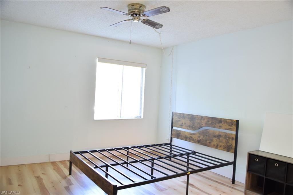 Room featuring wood-finish flooring, a window with blinds, and a ceiling fan