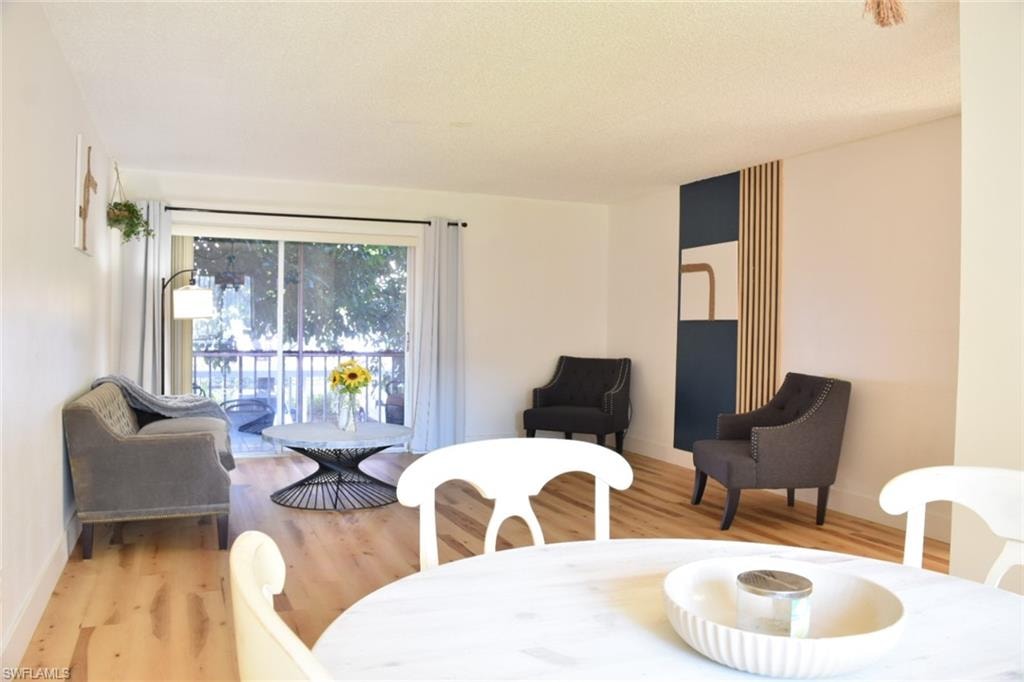 Open-concept living area with wood-finish flooring, a sliding glass door leading to a private balcony, and a decorative wall panel