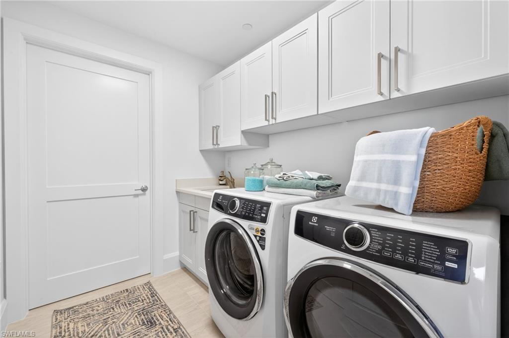 Laundry room features a sink , full size washer and dryer with lots of extra cabinets