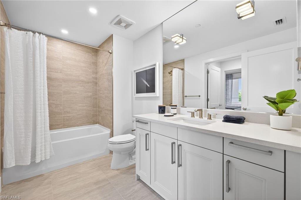 Bathroom featuring a white vanity with dual sinks, a large wall-mounted mirror, and contemporary fixtures