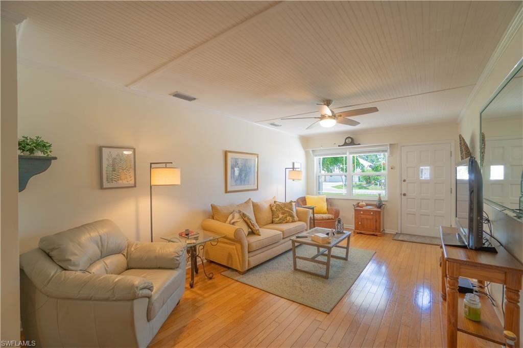 Living area with light wood-style flooring, crown molding, and a ceiling fan