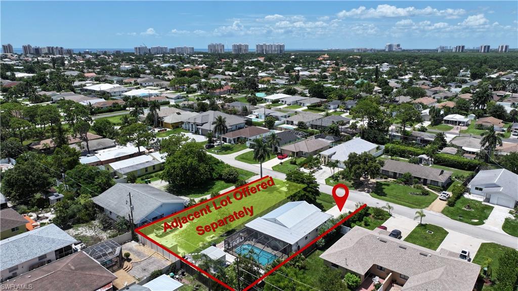 Aerial perspective showcasing a residential property with a screened pool, situated within a developed neighborhood