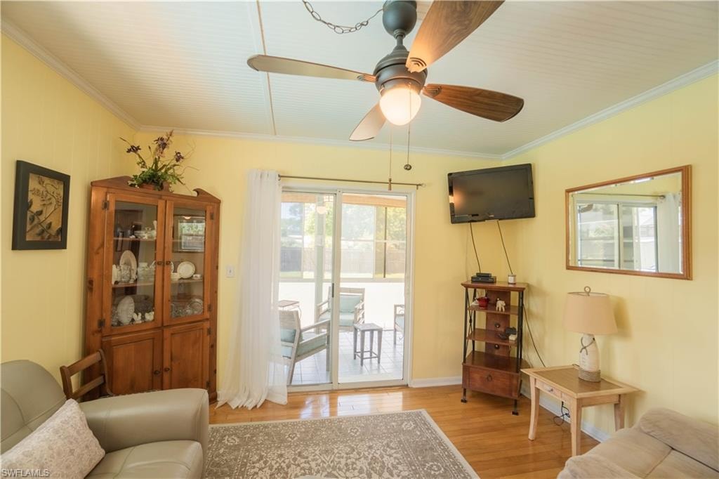 Living area featuring ornamental molding, light wood finished floors, and a ceiling fan