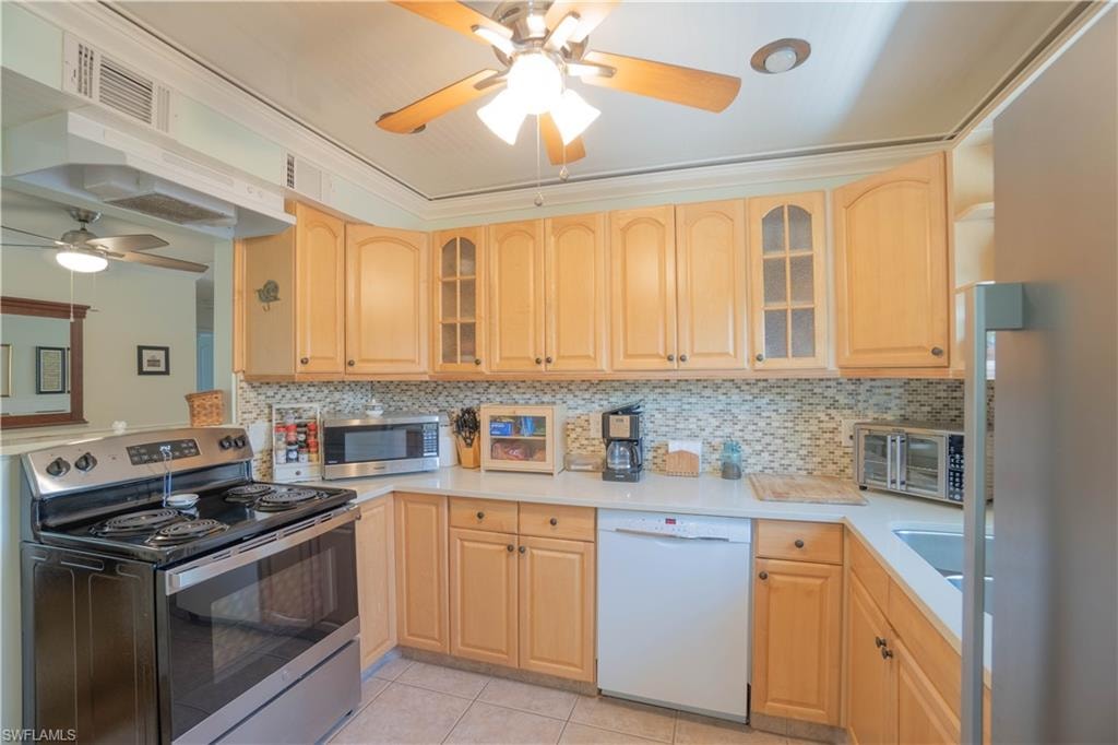 Kitchen featuring appliances with stainless steel finishes, glass insert cabinets, under cabinet range hood, and ceiling fan