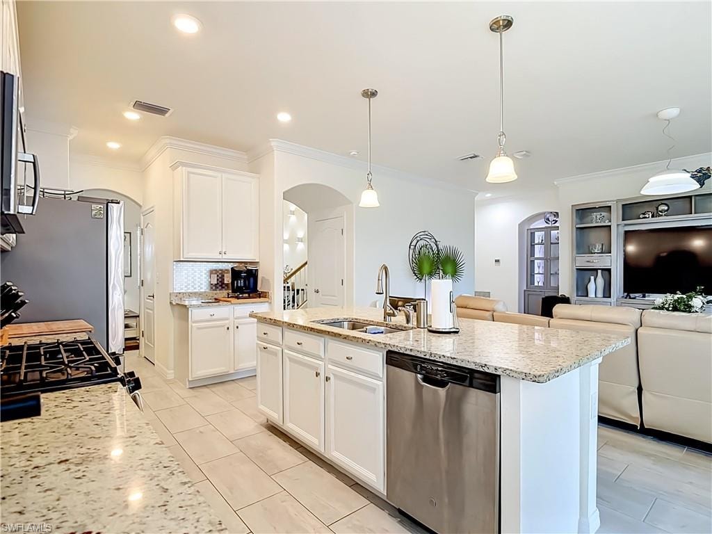 Well-appointed kitchen featuring granite countertops, white cabinetry, stainless steel appliances, a center island with a built-in sink, and recessed lighting