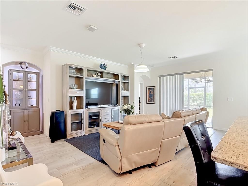 Spacious living area featuring light wood-finish flooring, a contemporary ceiling fan, recessed lighting, crown molding, and an arched entryway