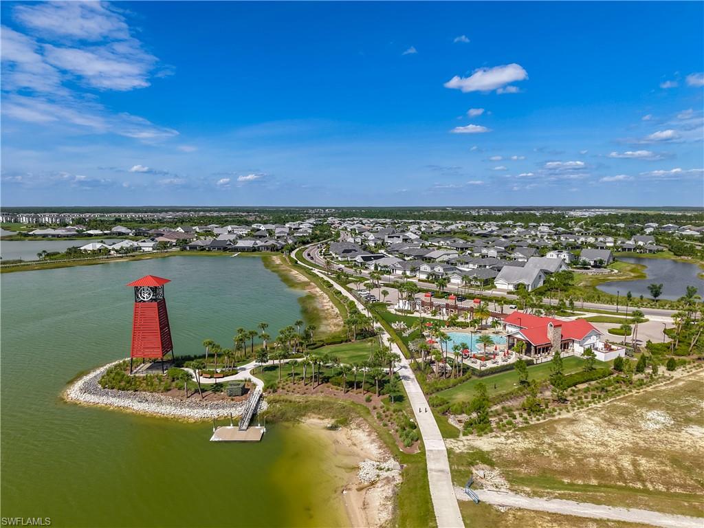 Community amenities featuring a prominent red clock tower, a dock extending into the lake, a resort-style swimming pool, and an expansive clubhouse with red roofing