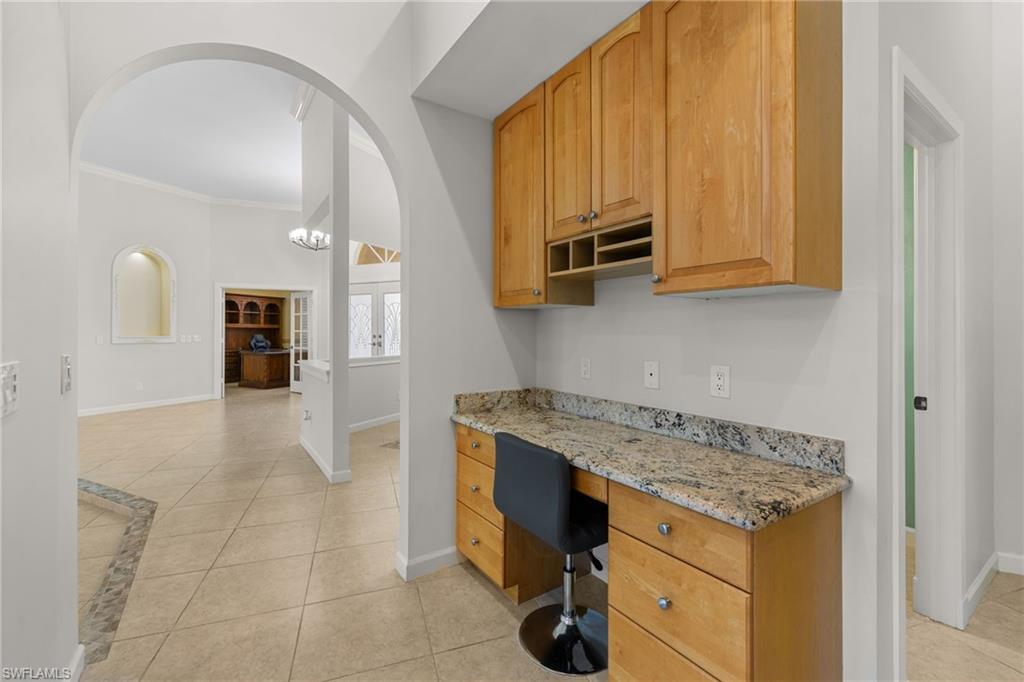 Built-in desk area featuring a granite-look countertop and wood cabinetry with metal hardware
