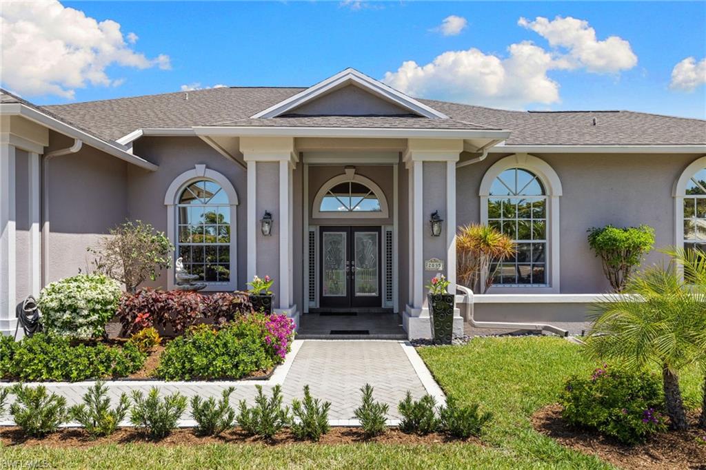 Stucco exterior featuring a prominent entryway with double glass doors