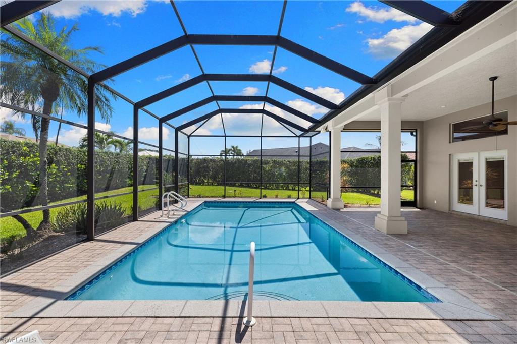 Screened pool enclosure featuring a rectangular pool with integrated steps and a paved deck