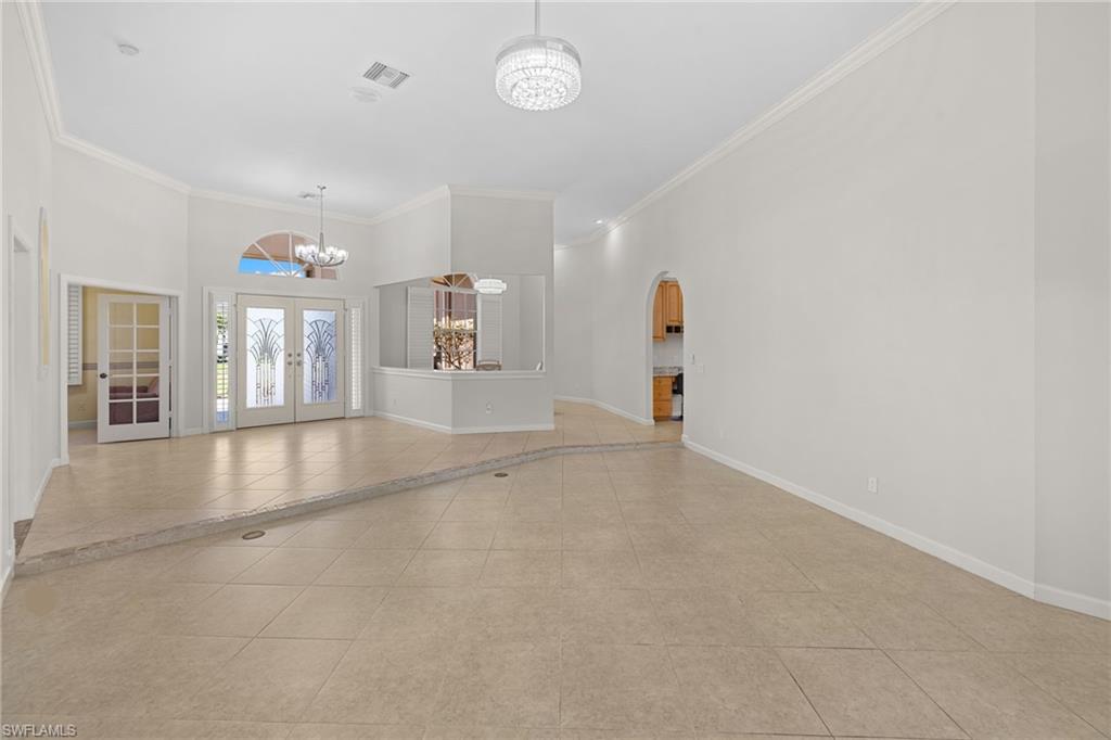 Spacious interior featuring neutral tile flooring, high vaulted ceilings, and crown molding