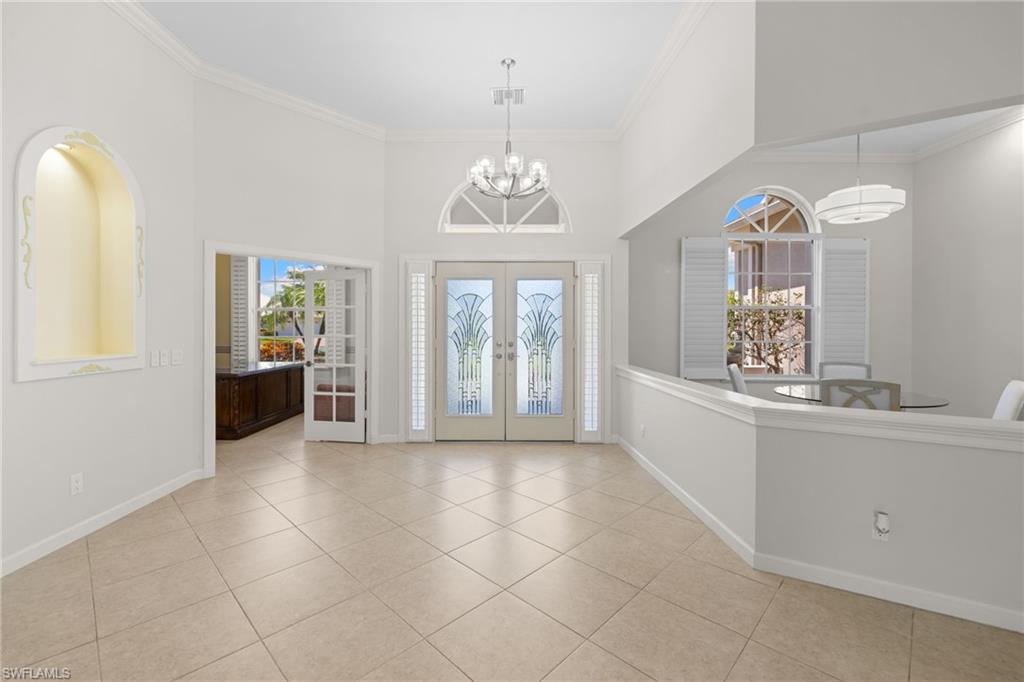 Grand entry foyer featuring double doors with decorative glass panels, an arched transom window, and a high vaulted ceiling