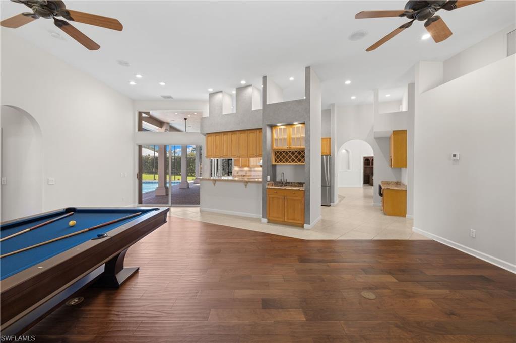 Spacious room with wood-finish flooring and high ceilings, featuring a built-in wet bar with wood cabinetry and a wine rack